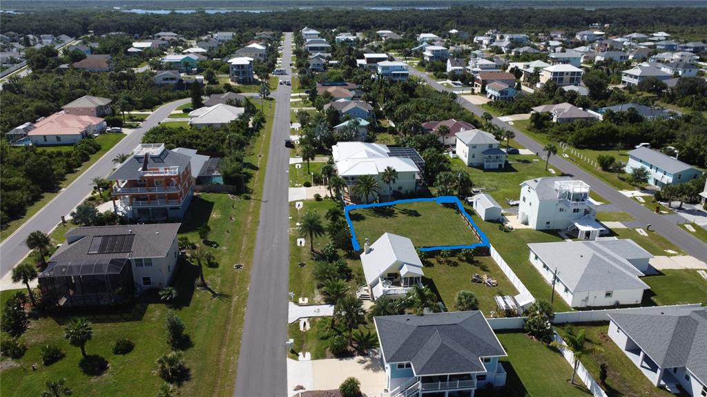 An aerial view shows a vacant residential lot outlined in blue within a coastal neighborhood — 47 ROLLINS DRIVE, PALM COAST, FL