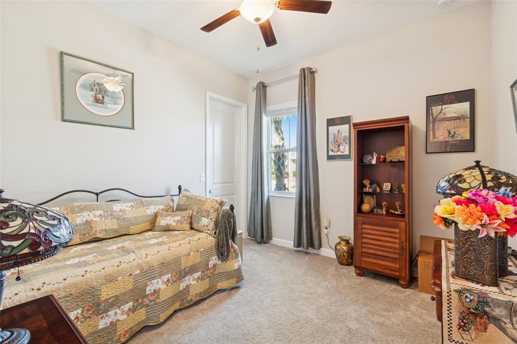 A bedroom features a daybed, a wooden bookshelf, a ceiling fan, and a window with curtains — 31516 CABANA RYE, SAN ANTONIO, FL