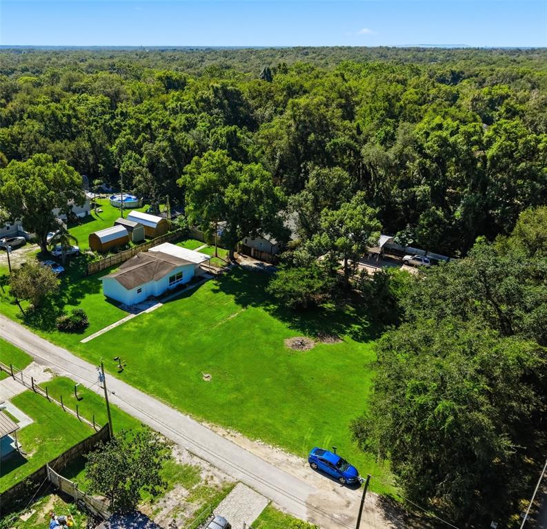 An aerial view shows a house with a large lawn, outbuildings, and surrounding dense trees — 39250 MIRAMAR DRIVE, ZEPHYRHILLS, FL