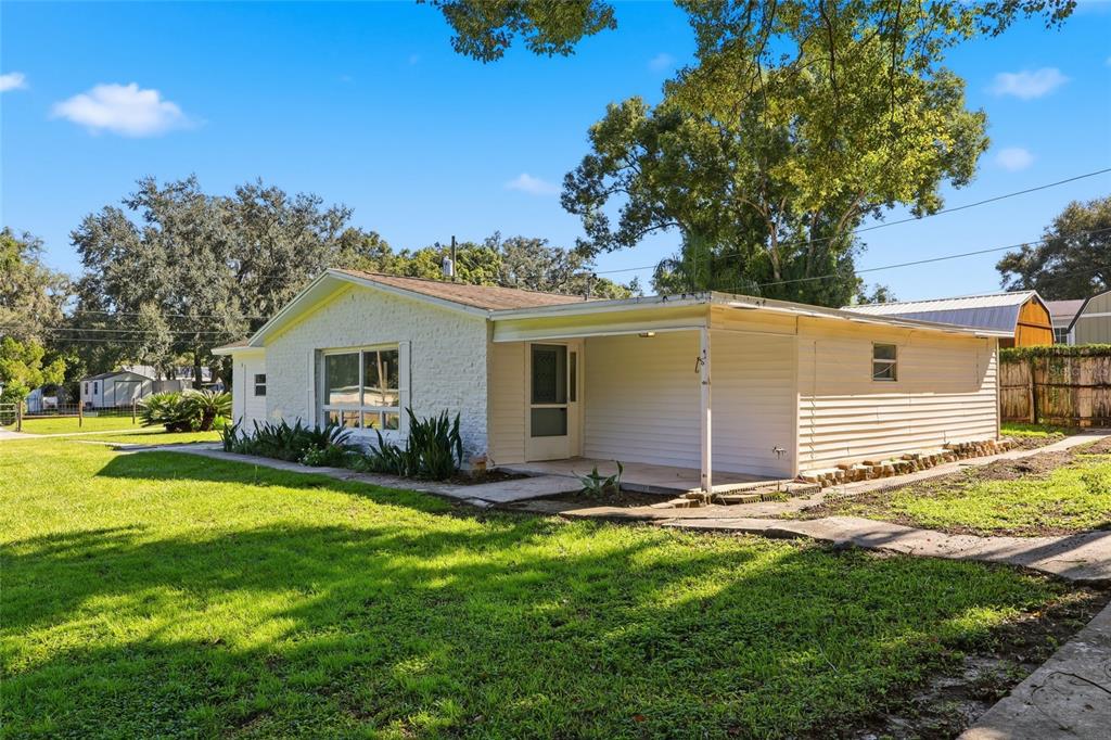 A single-story house with a white stone facade, a covered porch, and a grassy yard — 39250 MIRAMAR DRIVE, ZEPHYRHILLS, FL