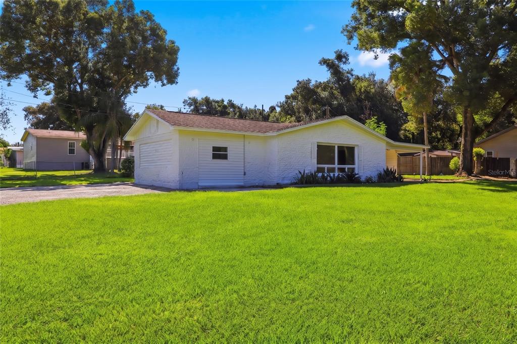 A white, single-story house with a textured exterior and a large front lawn — 39250 MIRAMAR DRIVE, ZEPHYRHILLS, FL