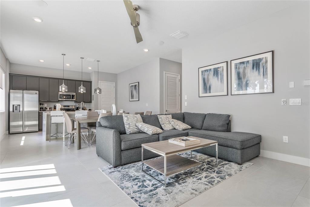 A modern open-concept living room and kitchen featuring a gray sectional sofa and stainless appliances — 7770 SANDY RIDGE DRIVE UNIT 110, REUNION, FL
