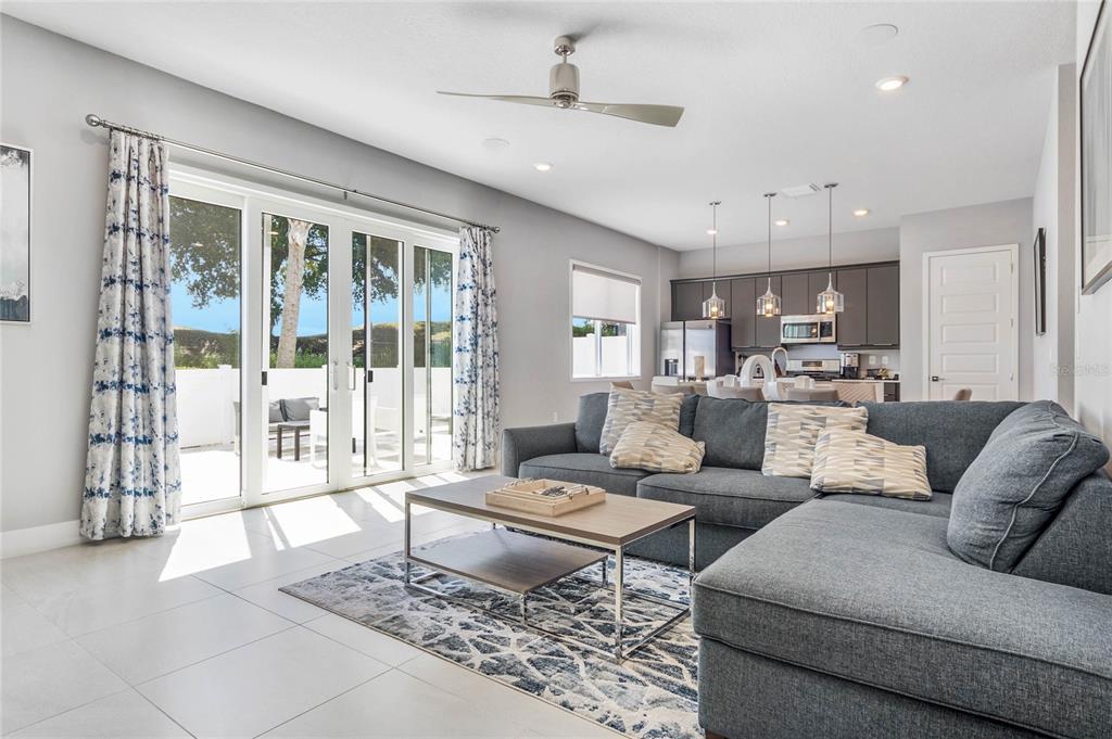 A living room with a gray sectional sofa, coffee table, and sliding glass patio doors — 7770 SANDY RIDGE DRIVE UNIT 110, REUNION, FL