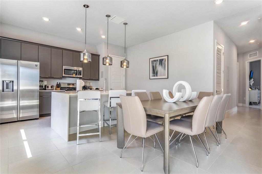 A modern kitchen and dining area features gray cabinetry, a white island, and neutral furniture — 7770 SANDY RIDGE DRIVE UNIT 110, REUNION, FL