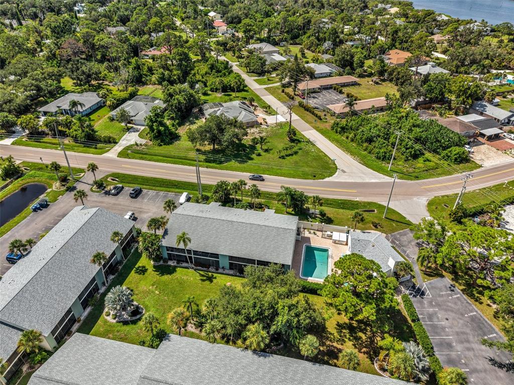 An aerial view shows a multi-unit residential complex with a swimming pool and parking lots — 1730 MANASOTA BEACH ROAD UNIT 115, ENGLEWOOD, FL