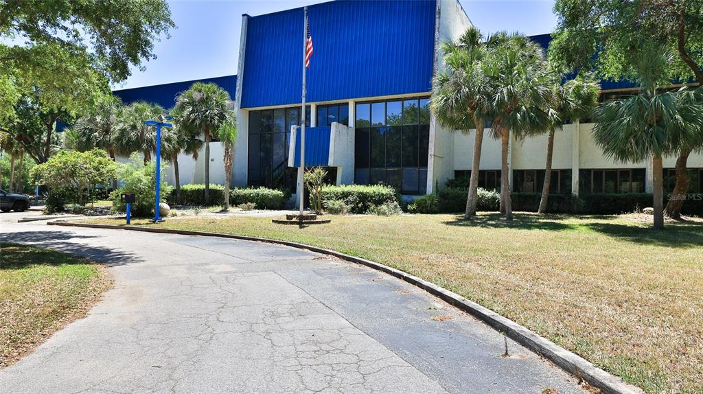 A two-story commercial building with blue metal siding, large windows, and a paved driveway — 2 COMMERCE BOULEVARD, PALM COAST, FL