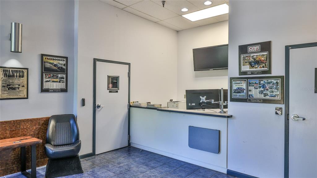 A reception area features a service counter, a car seat chair, and automotive-themed wall art — 2 COMMERCE BOULEVARD, PALM COAST, FL