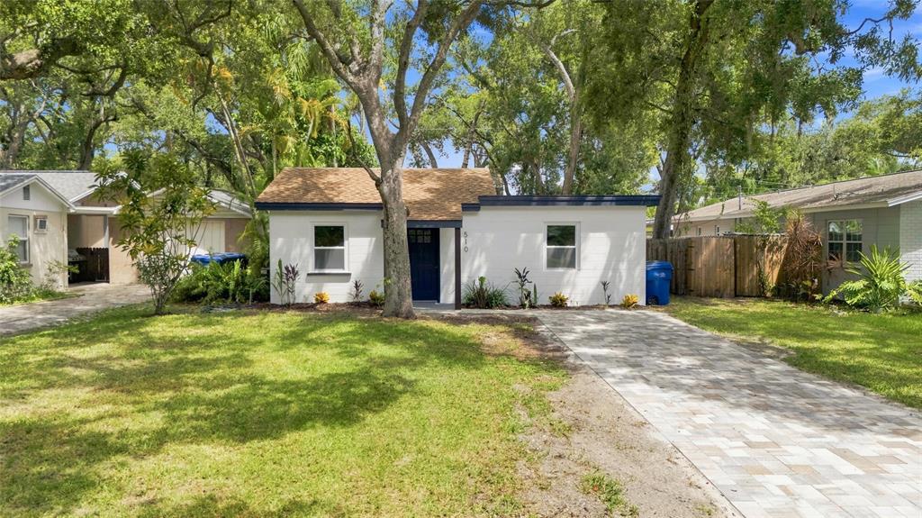A white single-story house with a paved driveway and mature trees in the front yard — 510 3RD AVENUE NE, LARGO, FL