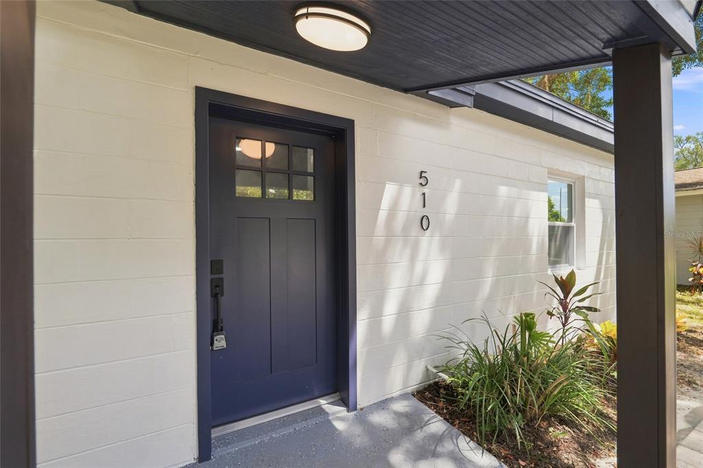 A dark blue front door with a window sits on a white painted brick exterior — 510 3RD AVENUE NE, LARGO, FL