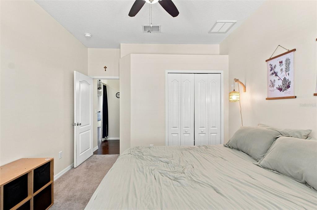 A bedroom features a bed with sage bedding, black curtains, and two wall-mounted light fixtures — 4327 CANONGATE COURT, SPRING HILL, FL