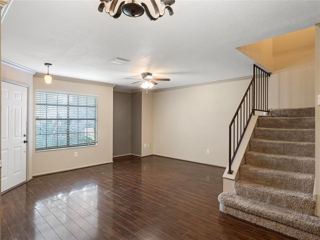A living room features dark wood flooring, a carpeted staircase, and a ceiling fan — 2820 REVERE COURT, CASSELBERRY, FL