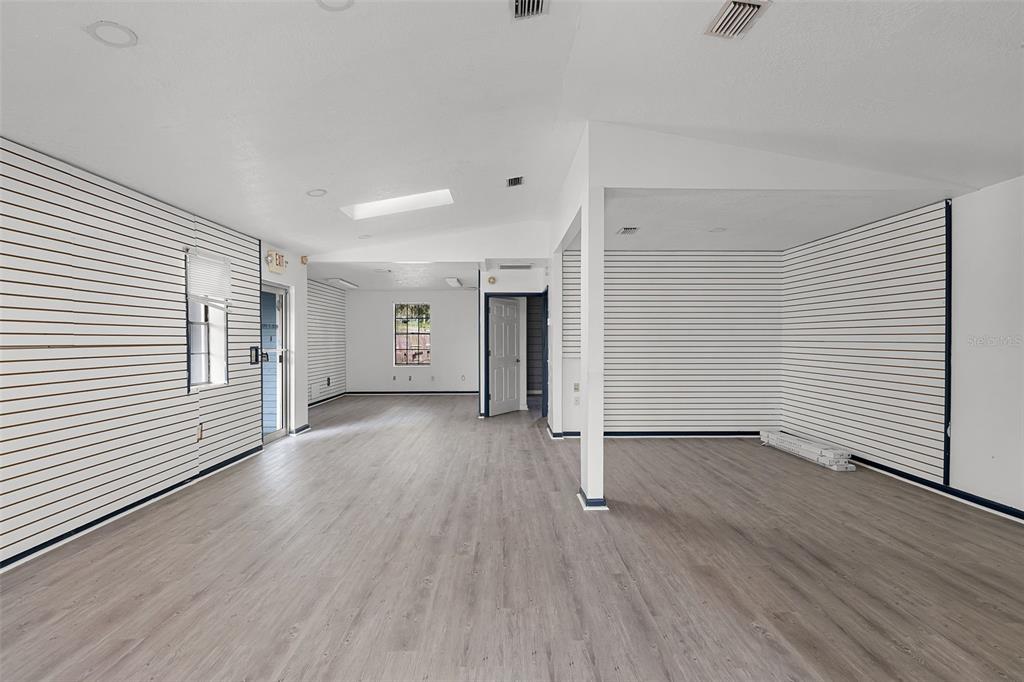 An empty room with light wood-look flooring and white slat walls throughout the space — 697 E ANDERSON ROAD, GROVELAND, FL