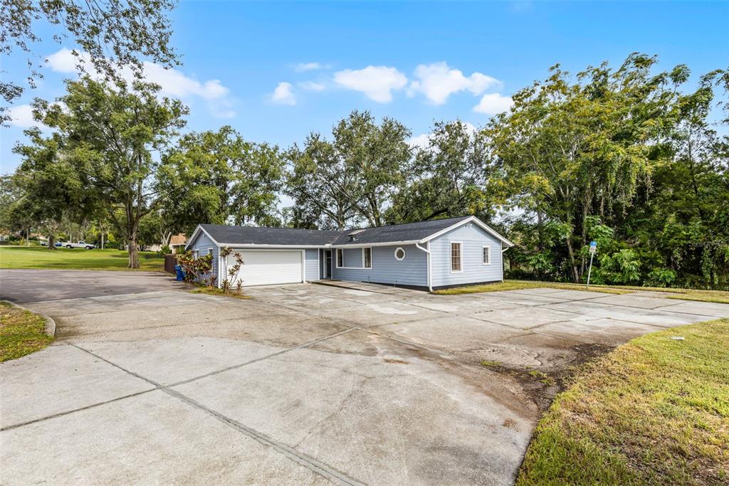 A light blue, single-story house with a large concrete driveway and an attached garage — 697 E ANDERSON ROAD, GROVELAND, FL