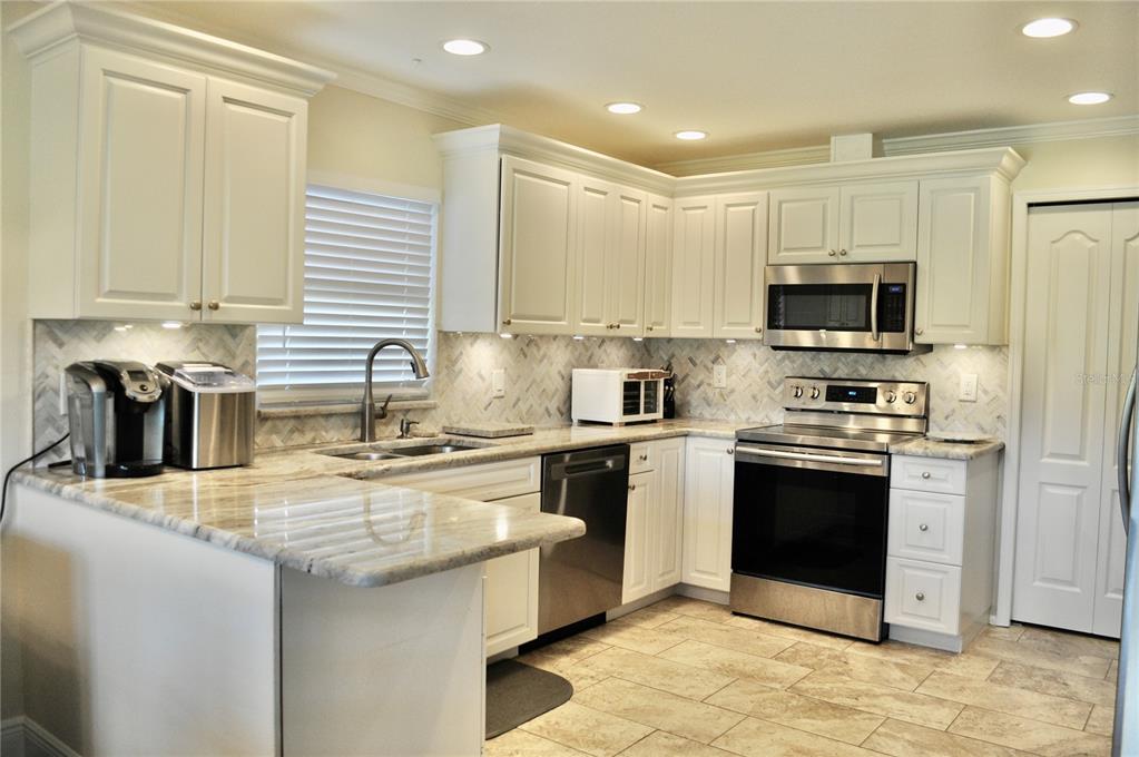 A kitchen with white cabinets, stainless steel appliances, and light-colored granite countertops — 150 POOLE PLACE, OLDSMAR, FL