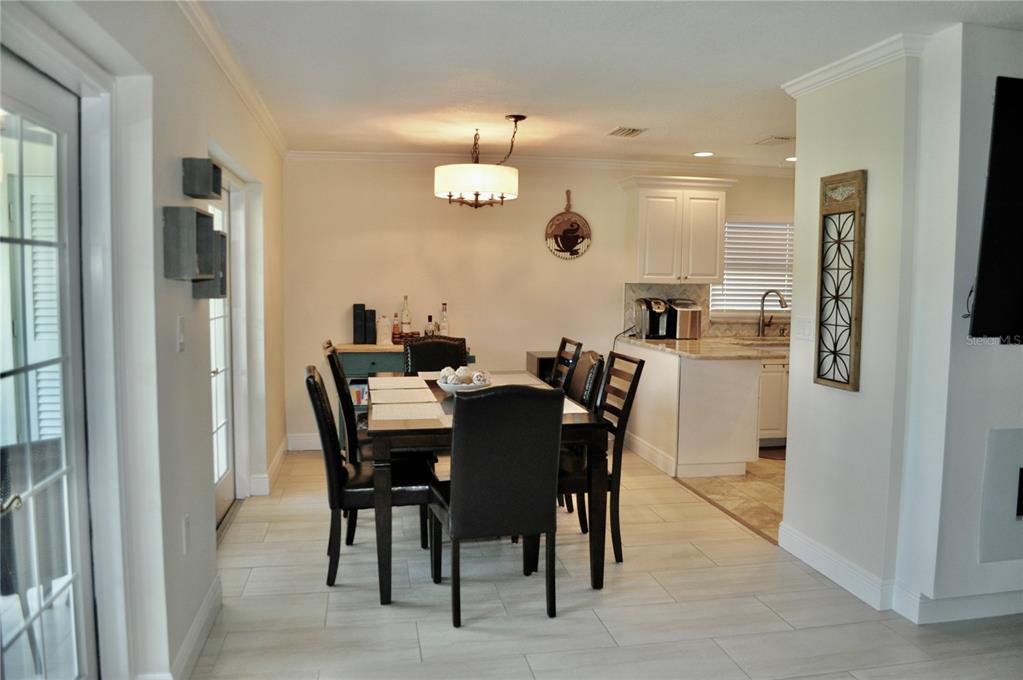 A dining area with a dark wood table and chairs sits adjacent to a white kitchen — 150 POOLE PLACE, OLDSMAR, FL