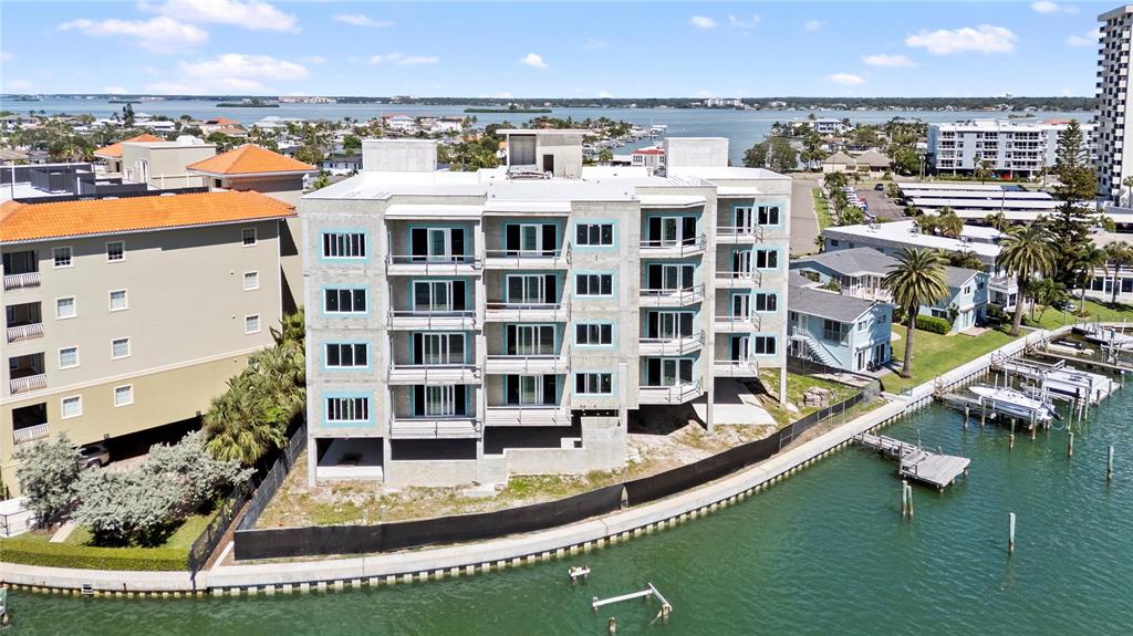 An aerial view shows a multi-story concrete apartment building under construction beside a waterway — 211 SKIFF POINT UNIT 2A, CLEARWATER, FL