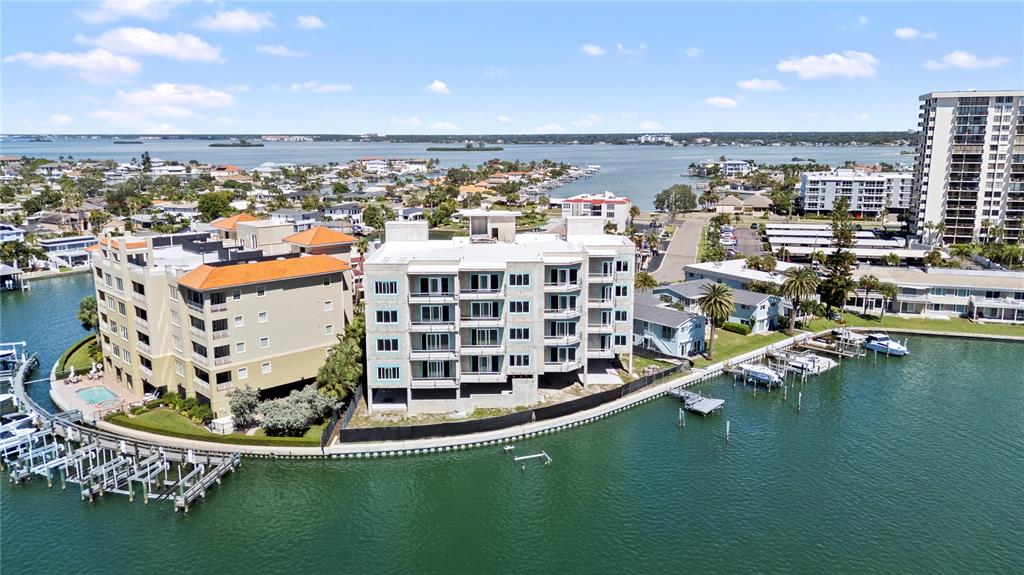 An aerial view shows waterfront residential buildings with boat docks along a canal — 211 SKIFF POINT UNIT 2A, CLEARWATER, FL