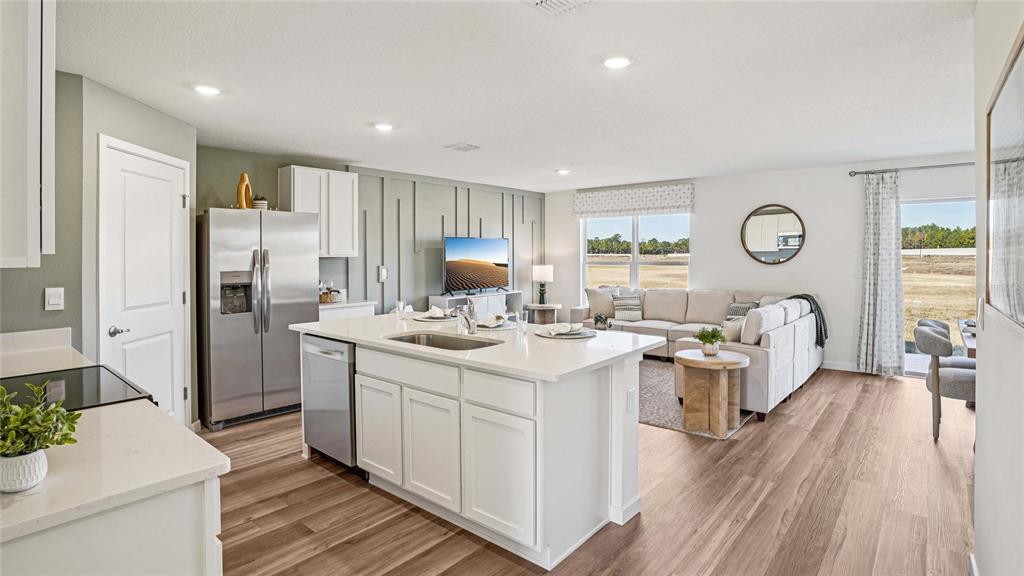 A modern open-concept kitchen and living room featuring white cabinetry, a center island, and furniture — 4584 KONA CIRCLE, SPRING HILL, FL