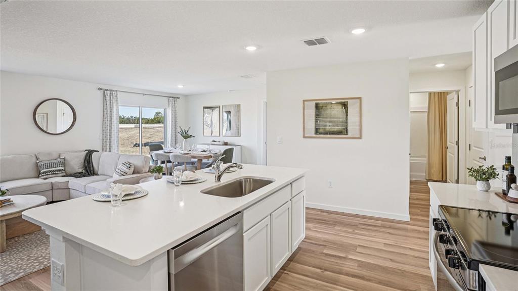 A kitchen island with a stainless steel sink overlooks an open-concept living and dining area — 4584 KONA CIRCLE, SPRING HILL, FL