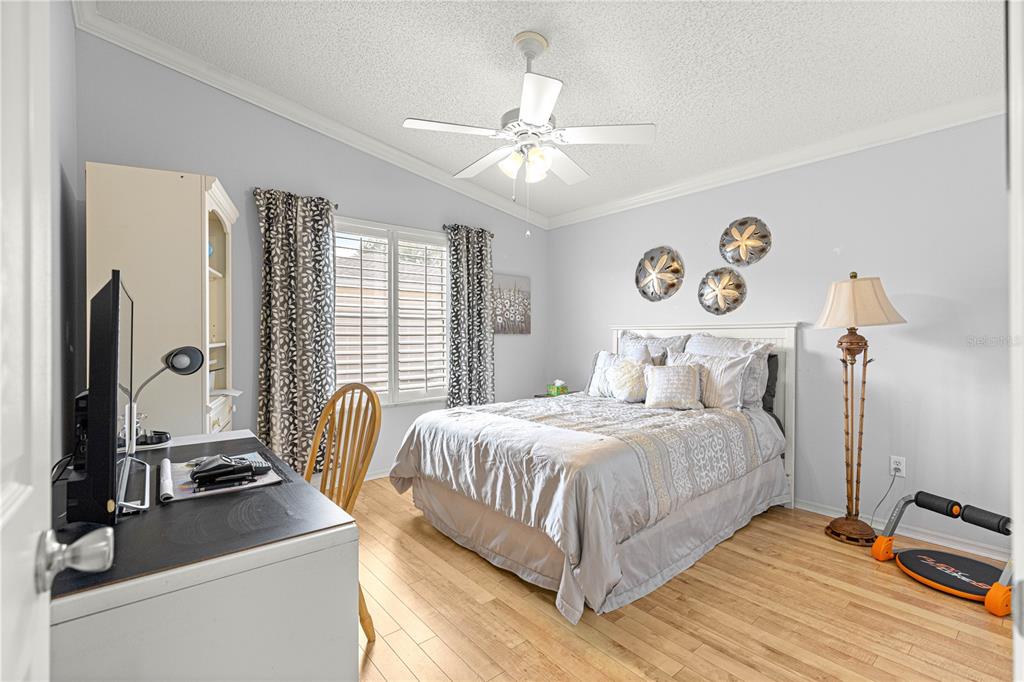 A bedroom features a bed, a desk, a ceiling fan, and light wood flooring — 1660 ORR TERRACE, THE VILLAGES, FL