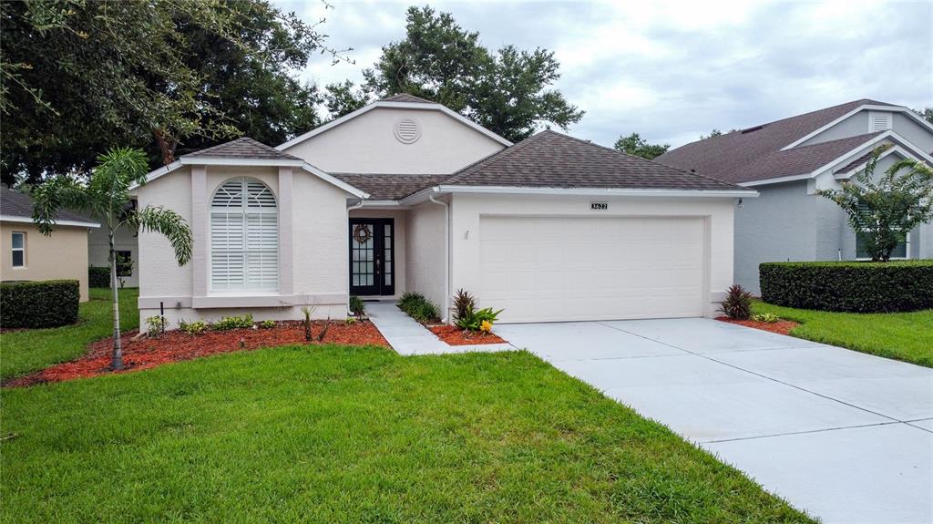 A single-story house with a beige stucco exterior, a two-car garage, and a front lawn — 3622 WESTERHAM DRIVE, CLERMONT, FL