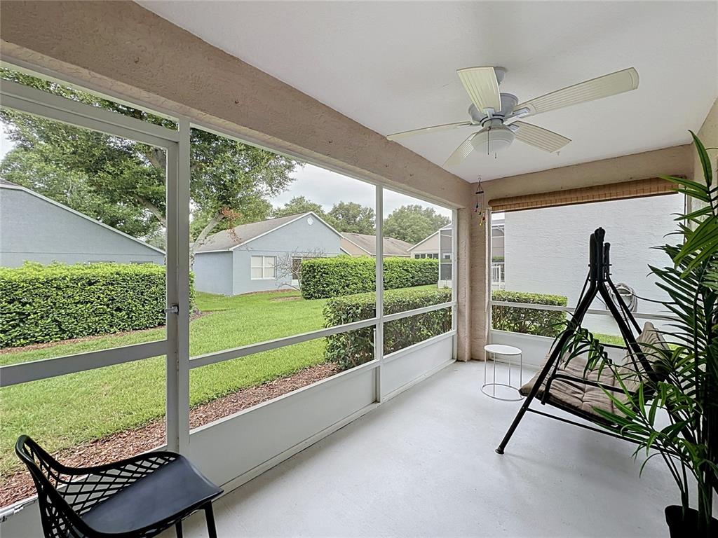 A screened-in porch features a ceiling fan, a swing, and views of a grassy backyard — 3622 WESTERHAM DRIVE, CLERMONT, FL