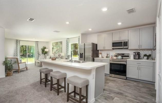 A kitchen with light gray cabinets and a central island overlooks a carpeted living area — 947 SALERNO COURT, KISSIMMEE, FL
