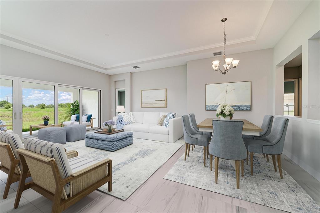 This open-concept living and dining room features a white sofa, blue accents, and sliding glass doors — 10183 LILAC MANOR TRACE, SAN ANTONIO, FL