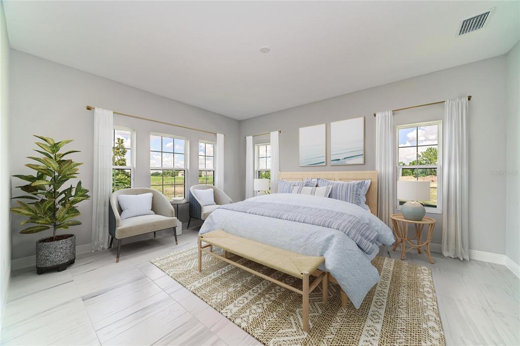 A bright bedroom features light gray walls, white tile floors, a bed, and two armchairs — 10183 LILAC MANOR TRACE, SAN ANTONIO, FL