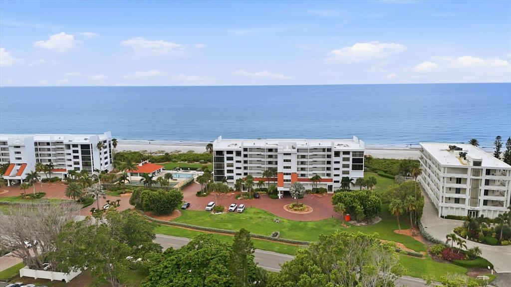 An aerial view of three beachfront apartment buildings with parking lots and surrounding green space — 4545 GULF OF MEXICO DRIVE UNIT 311, LONGBOAT KEY, FL