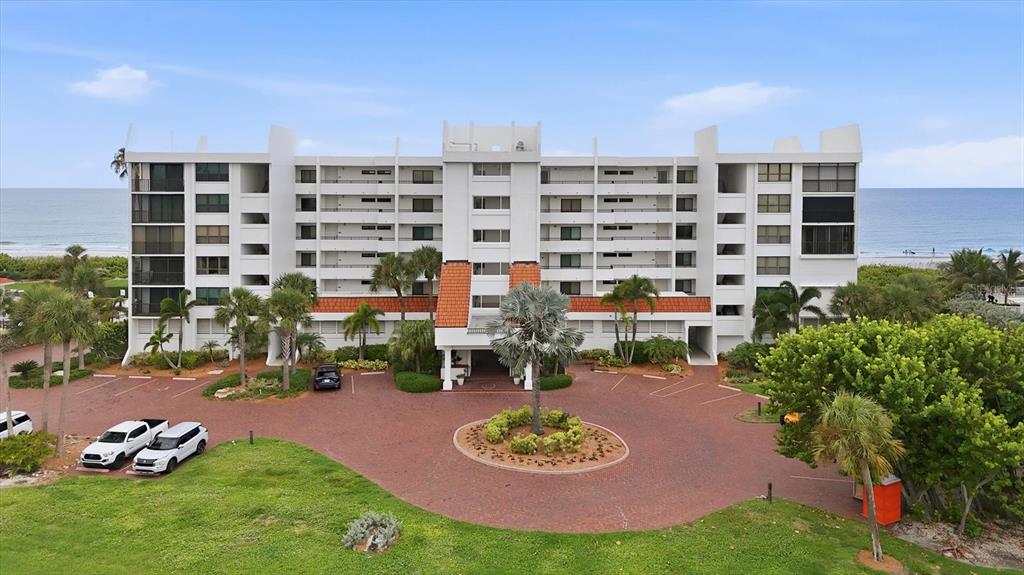 An aerial view of a multi-story white residential building with a circular brick driveway — 4545 GULF OF MEXICO DRIVE UNIT 311, LONGBOAT KEY, FL