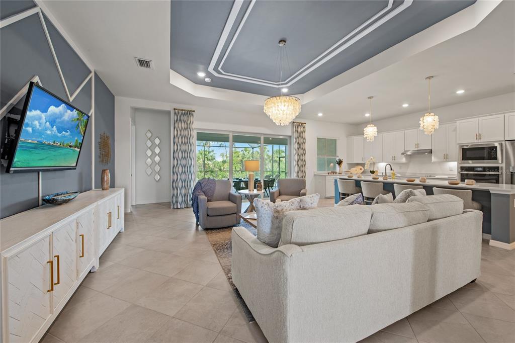 A spacious open-concept living room and kitchen featuring a tray ceiling and tile flooring — 7161 INLET ISLES COURT, LAKEWOOD RANCH, FL