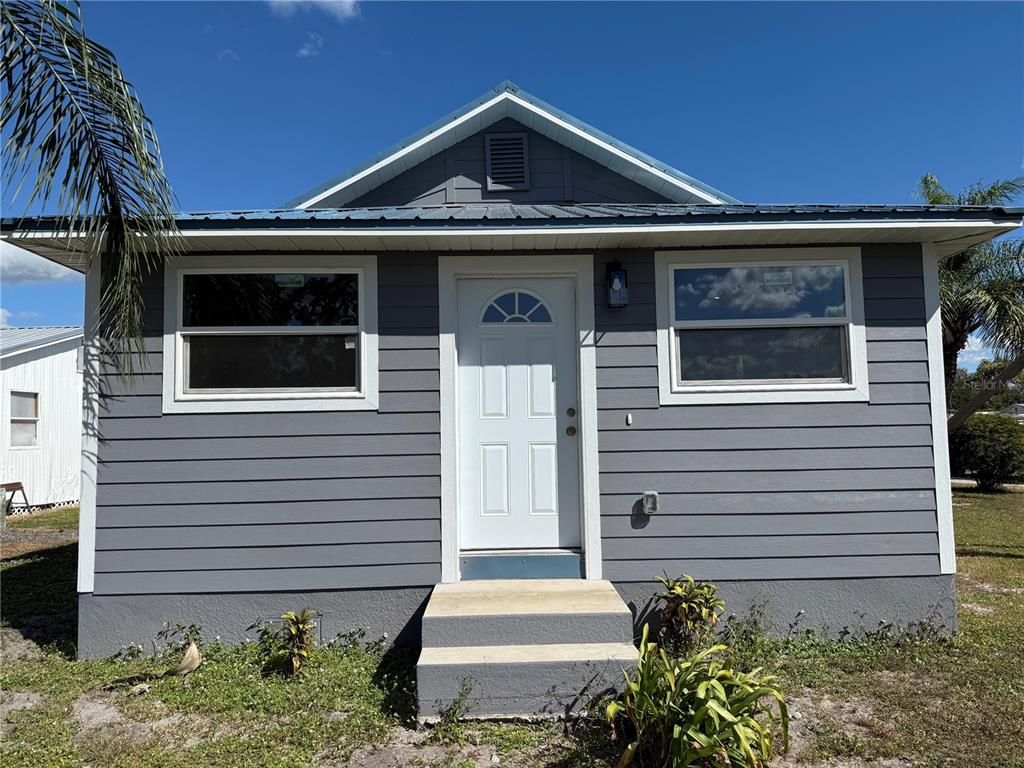 A gray, single-story house with a white front door and a metal roof — 103 S ROGERS AVENUE, ARCADIA, FL