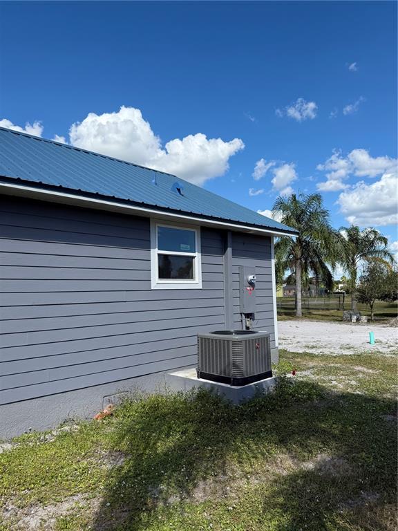 The exterior of a gray house features a blue metal roof and an HVAC unit — 103 S ROGERS AVENUE, ARCADIA, FL