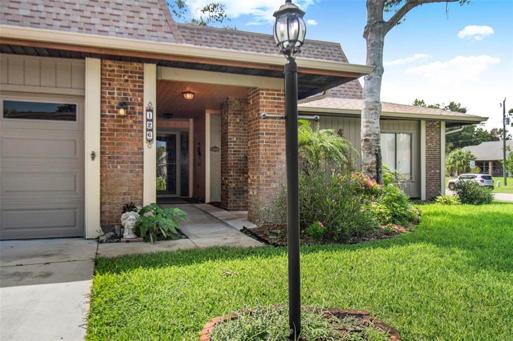 A brick and siding house exterior features a front porch, a garage, and a lamp post — 126 FLORIDA PARK DRIVE, PALM COAST, FL