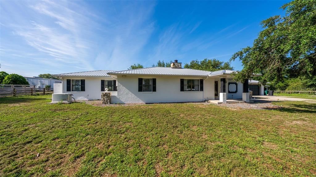 A white, single-story house with a metal roof and black shutters sits on a lawn — 12650 SE 98TH LANE, DUNNELLON, FL