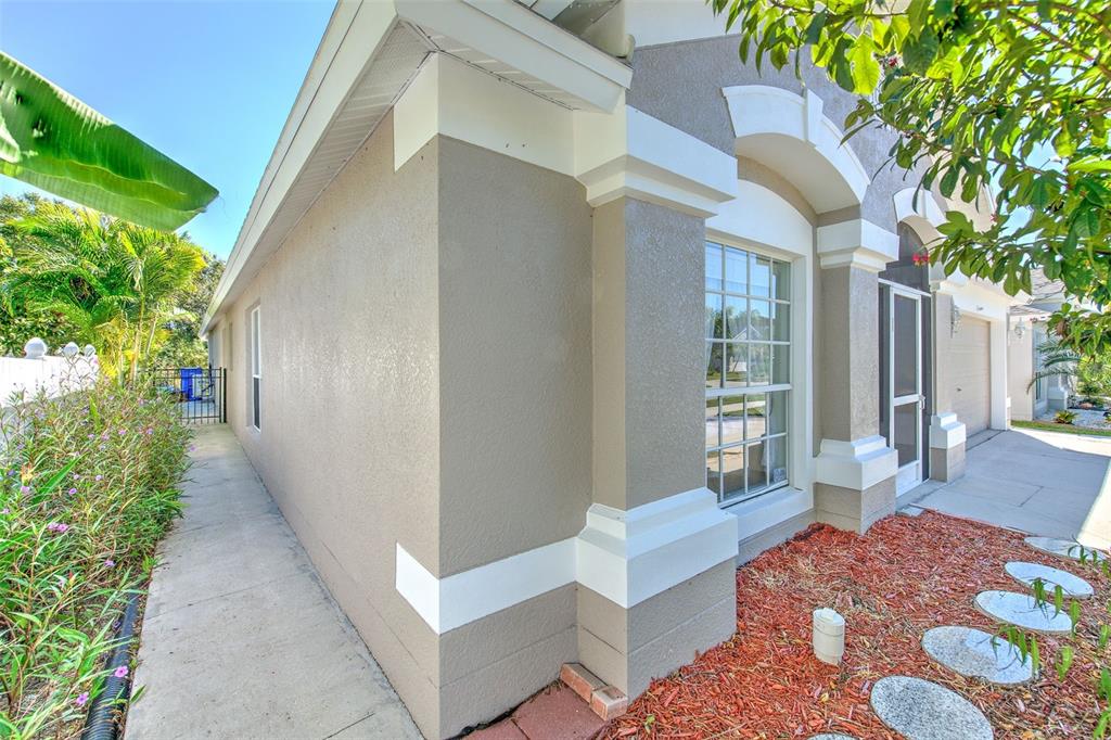 A side view of a beige stucco house with white trim and a concrete walkway — 13326 EVENING SUNSET LANE, RIVERVIEW, FL