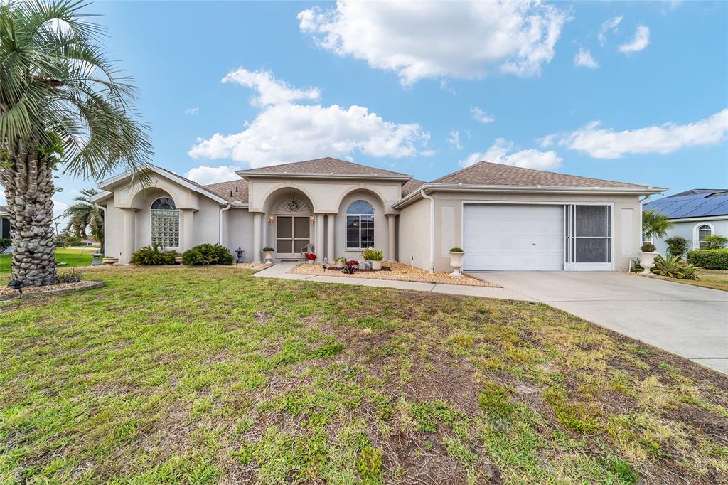 A single-story stucco house with a two-car garage, arched entryways, and a palm tree — 5245 NW 21ST LOOP, OCALA, FL