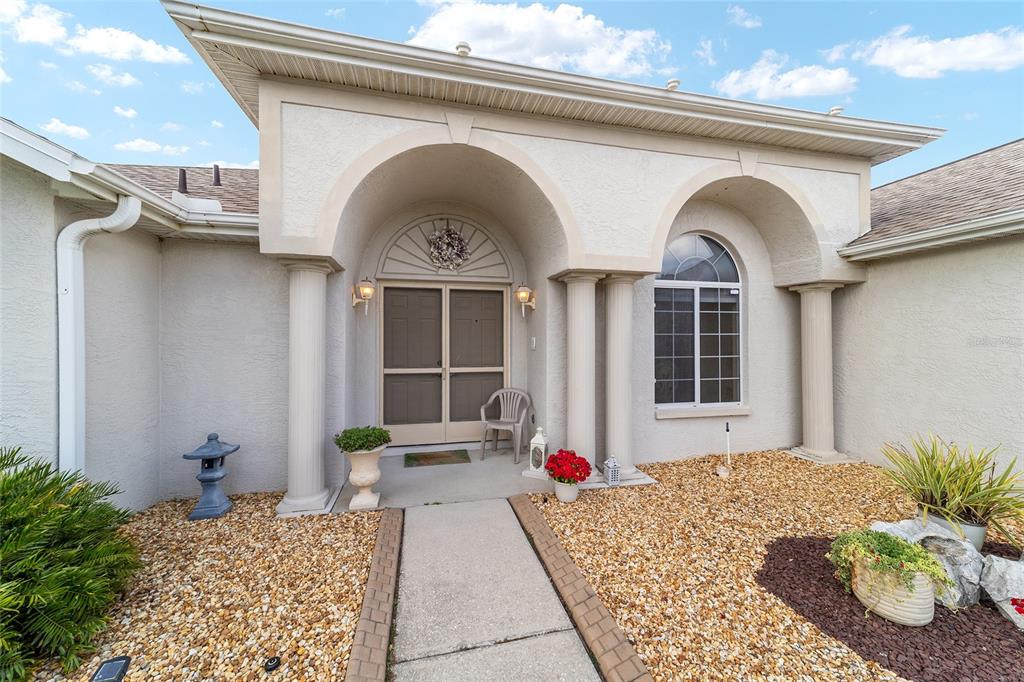 The exterior of a house features a covered entryway with columns and a stone walkway — 5245 NW 21ST LOOP, OCALA, FL