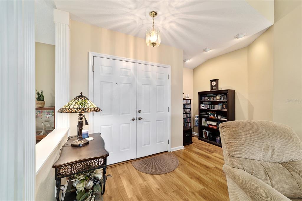An entryway features double white doors, wood-look flooring, a stained-glass lamp, and a tall bookshelf — 5245 NW 21ST LOOP, OCALA, FL