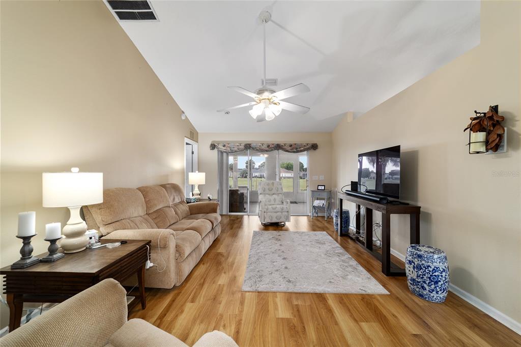 A living room features a beige sofa, a television on a console, and wood flooring — 5245 NW 21ST LOOP, OCALA, FL