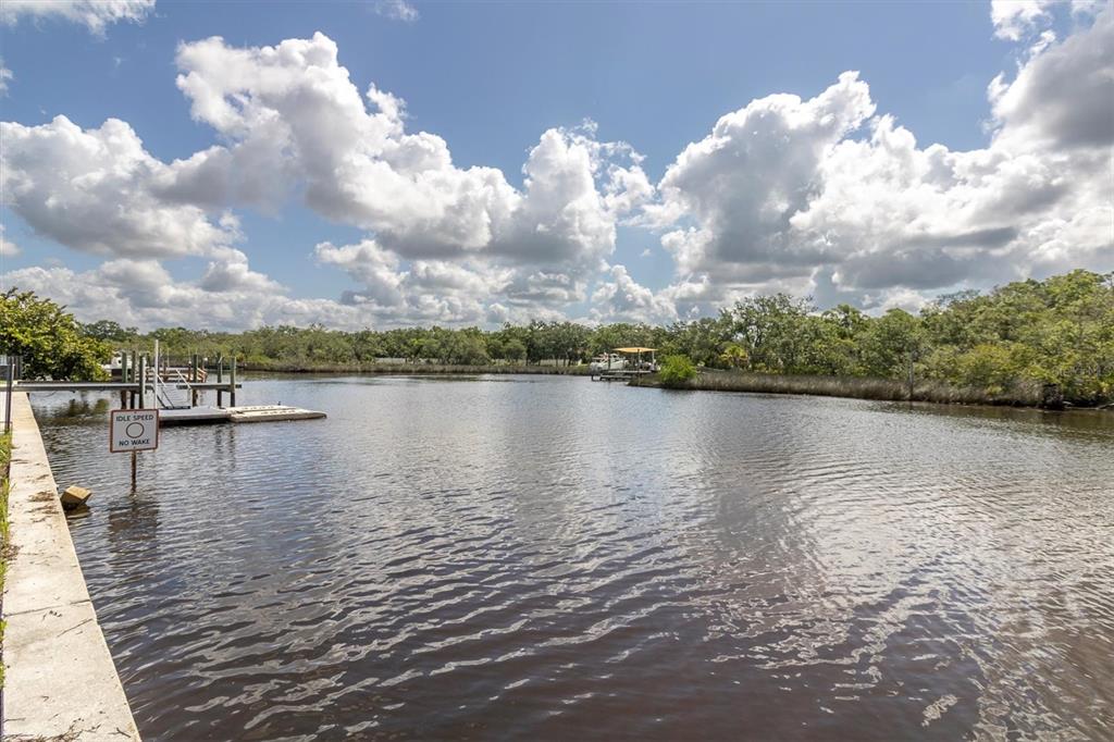 A view of a calm waterway with a wooden dock and a no-wake sign — FLOTILLA, HOLIDAY, FL