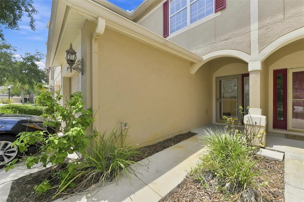 A beige stucco house exterior features a covered entryway, a walkway, and a side garage — 2823 CONCH HOLLOW DRIVE, BRANDON, FL