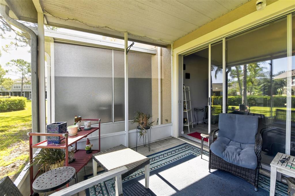 A covered patio features a tiled floor, outdoor furniture, and sliding glass doors leading indoors — 2823 CONCH HOLLOW DRIVE, BRANDON, FL