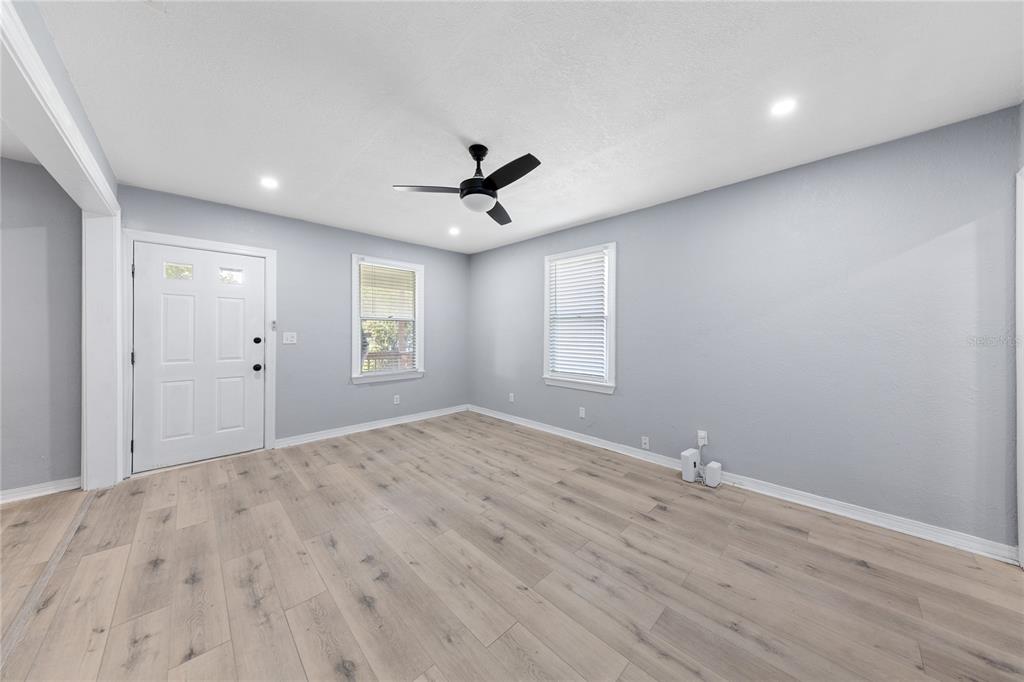 An empty room with light wood-look flooring, gray walls, two windows, and a ceiling fan — 3861 GALICIA ROAD, JACKSONVILLE, FL