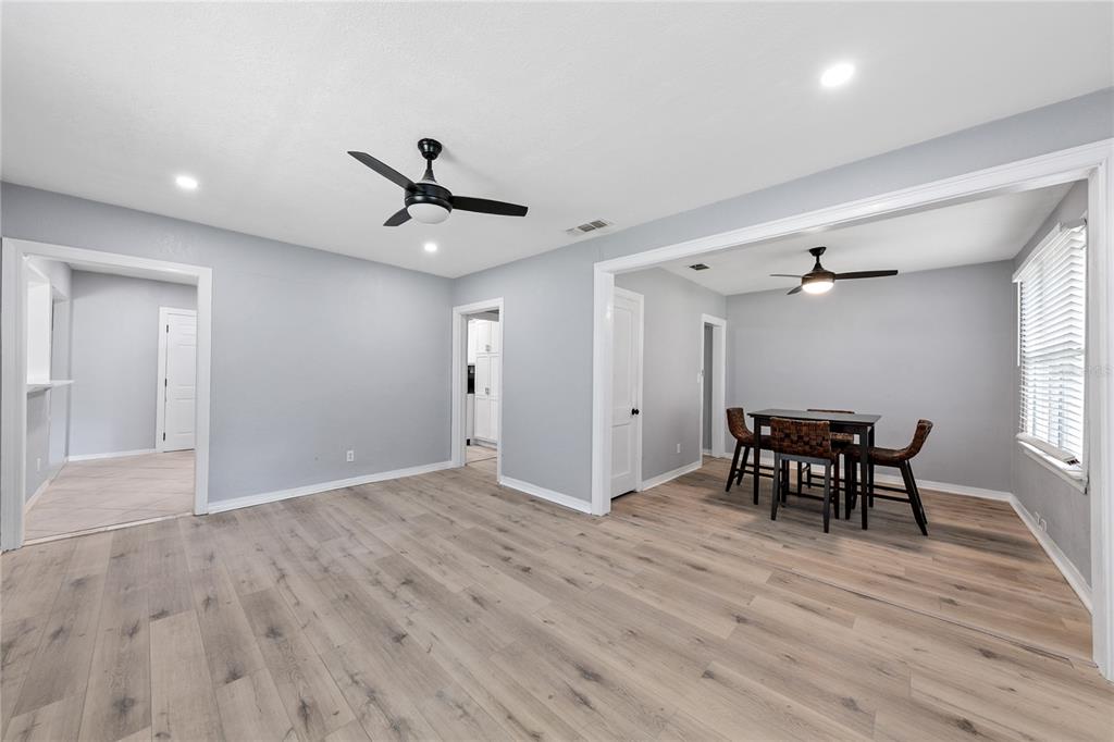 An open-concept living and dining area features light wood-look flooring, gray walls, and ceiling fans — 3861 GALICIA ROAD, JACKSONVILLE, FL