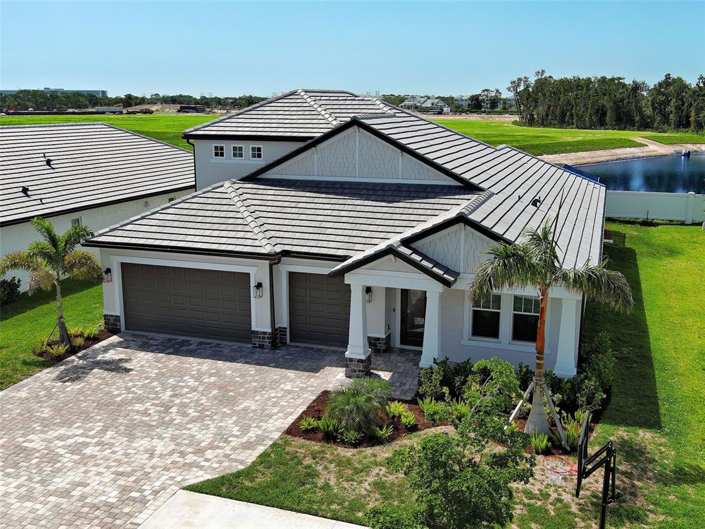 An aerial view of a suburban house with a tiled roof, paver driveway, and garage — 1684 LUGANO CIRCLE, NOKOMIS, FL