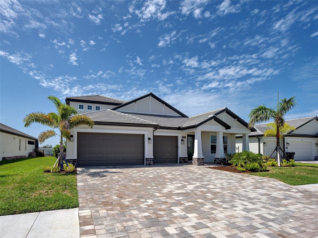 A single-story house with a paver driveway, three-car garage, and palm trees under a sky — 1684 LUGANO CIRCLE, NOKOMIS, FL