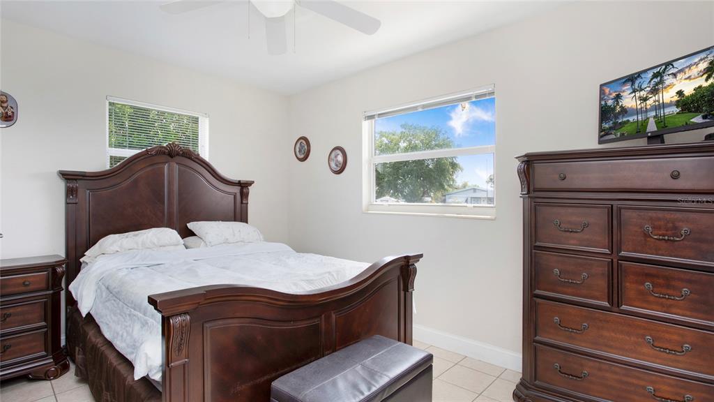 A bedroom features a dark wood bed frame, matching dresser, and two windows — 515 YORK ROAD, LEHIGH ACRES, FL