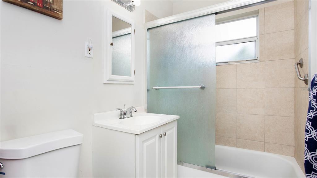 A bathroom features a white vanity, a toilet, and a shower-tub combination with glass doors — 515 YORK ROAD, LEHIGH ACRES, FL